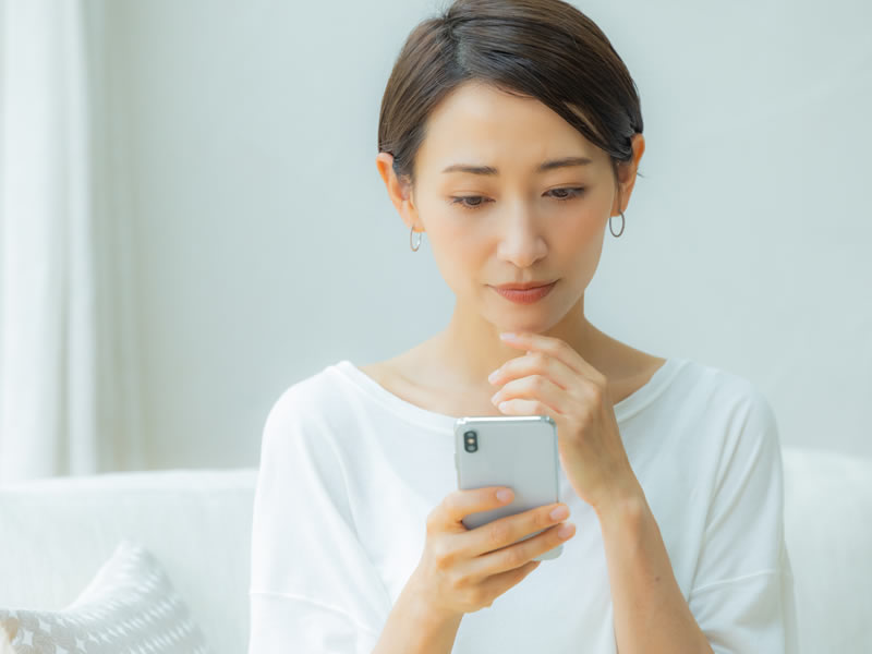 スマフォで銀座の美容皮膚科を調べている女性